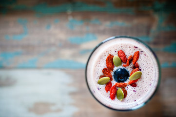 Healthy smoothie made from blended pineapple and kefir yogurt topped with pumpkin seeds, goji berries and a blueberry. Served on a wooden tray, this is a healthy, nutritious breakfast
 - obrazy, fototapety, plakaty