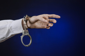 the hand of man in a white shirt with handcuffs in studio