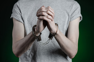 man with handcuffs on his hands in blue jeans on a dark green