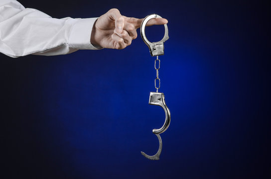 the hand of man in a white shirt with handcuffs in studio