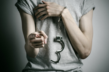 man with handcuffs on his hands in a gray T-shirt  in the studio