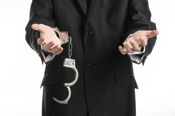 businessman in a black suit with handcuffs on his hands studio