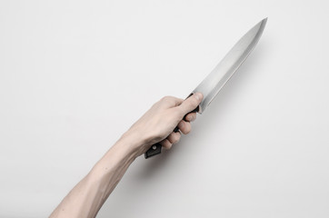 A man's hand reaching for a knife isolated on a gray background
