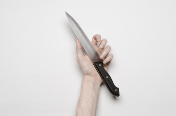 A man's hand reaching for a knife isolated on a gray background