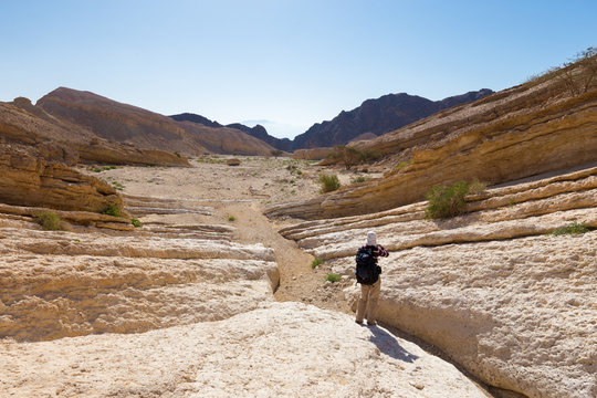 Backpacker hiking stone desert trail.