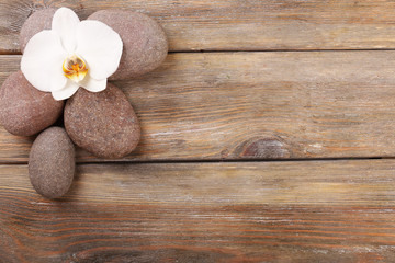 Spa stones and orchid flower on wooden background