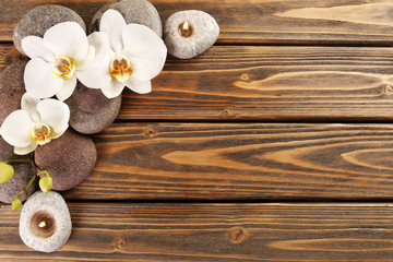 Spa stones and orchid flower on wooden background
