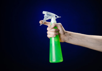 man's hand holding a green spray bottle for cleaning in studio