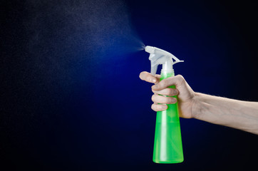 man's hand holding a green spray bottle for cleaning in studio