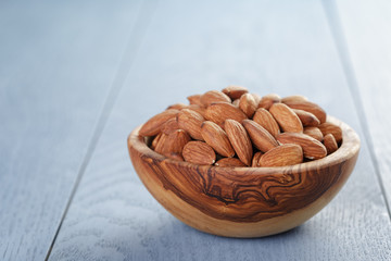 roasted almonds in bowl on blue wooden table with copy space