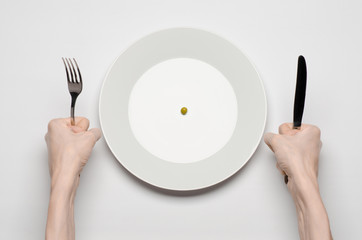 hands holding knife and fork on a plate with green peas