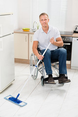 Fototapeta na wymiar Disabled Man On Wheelchair Cleaning Floor