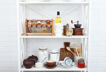 Fototapeta na wymiar Kitchen shelving with dishes on white brick wall background