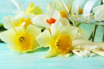 Fresh narcissus flowers on color wooden table, closeup