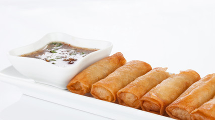 crispy spring rolls on white dish with Sweet & Sour Sauce.
