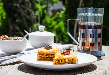 pieces of sweet baklava on the plate, green garden background