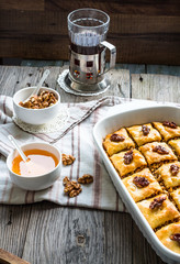 Turkish homemade baklava with honey and walnuts in a white bowl