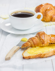 Fresh croissant with lemon curd and cup of coffee