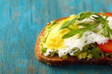 Tasty sandwich with egg, avocado and vegetables on wooden background