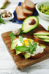 Tasty sandwiches with egg, avocado and vegetables on wooden background