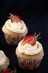 Capcakes with strawberries on dark background