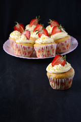 Capcakes with strawberries on dark background