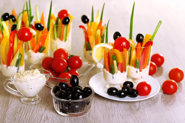 Snack of vegetables in glassware on wooden background