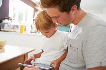 Father And Son Using Digital Tablet At Breakfast Table