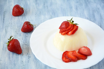 Panna cotta with strawberries on white plate