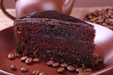 Delicious chocolate cake with coffee beans on plate on table close up