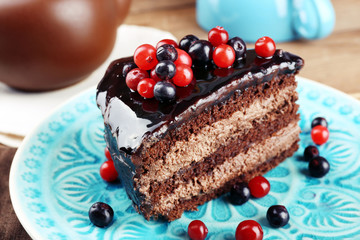 Delicious chocolate cake with berries on plate on table close up