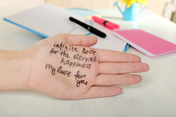 Female hand with written message on work place background