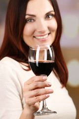 Young woman tasting wine on bright background
