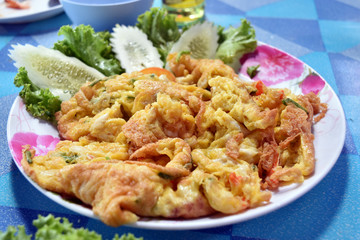Fried beaten egg with cucumber in dish on table.