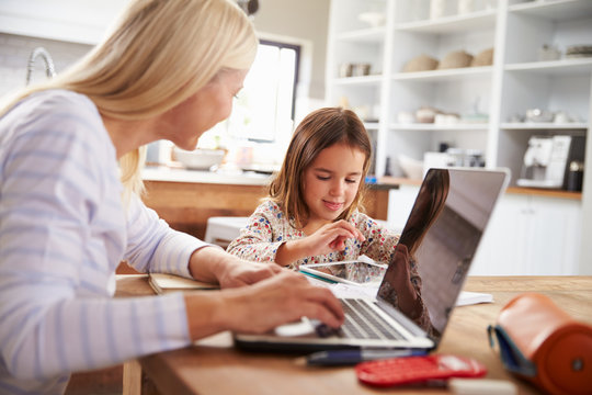 Mother using laptop computer with her young daughter
