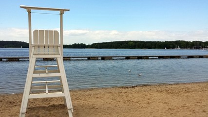White, wooden lifeguard chair on the beach by the lake.