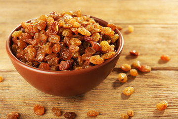 Raisins in bowl on wooden table, closeup