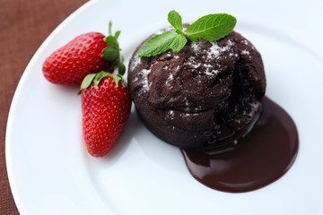 Chocolate fondant with strawberries on white plate, closeup