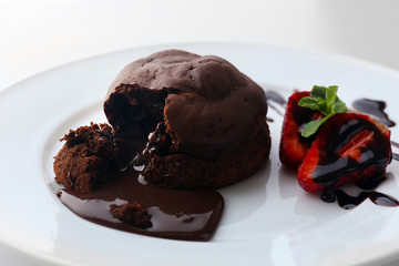 Chocolate fondant with strawberries on white plate, closeup