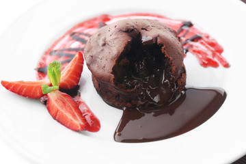 Chocolate fondant with strawberries on white plate, closeup