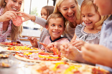 Two women making pizza with kids