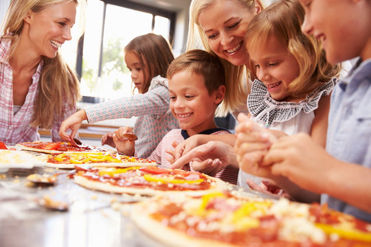 Two women making pizza with kids