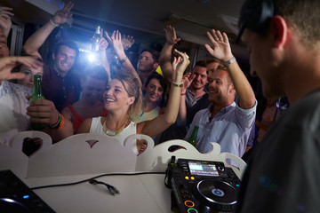 People Dancing In Nightclub With DJ In Foreground