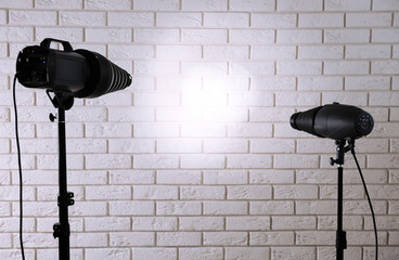 Photo studio with lighting equipment on brick wall background