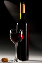  Filled glass of red wine and opened wine bottle