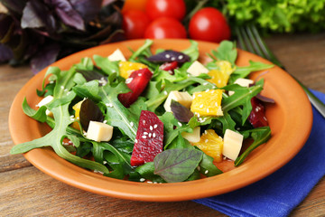 Tasty salad with arugula leaves in plate on wooden table, closeup