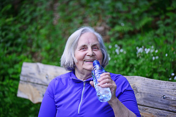 Fototapeta premium Seniorin trinkt Wasser aus der Flasche
