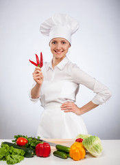 Happy young smiling female cook holding fresh cayennes