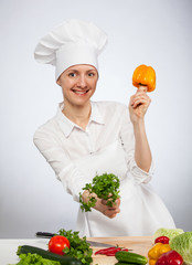 Smiling young cook holding parsley and yellow pepper