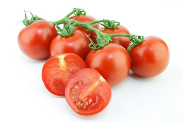 Fresh ripe "Garden Pearl" tomatoes (Solanum lycopersicum) on a vine, on a white background.